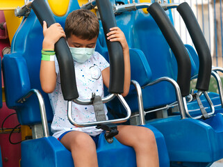 A child adjusts the safety seat of an amusement park ride.