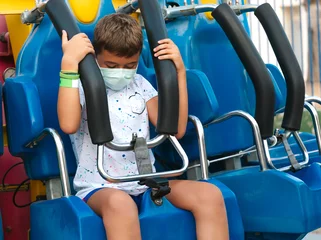 Tuinposter A child adjusts the safety seat of an amusement park ride. © Antonio