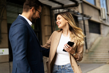 Young businesswoman and businessman standing on the street Beautiful businesswoman talking with her colleague.