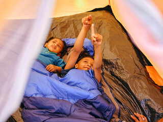 Sisters lying in tent under sleeping bag © Cultura Creative