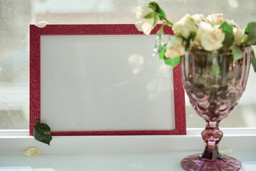 Pink frame mock up with sunlight and wineglass with white roses. Selective focus