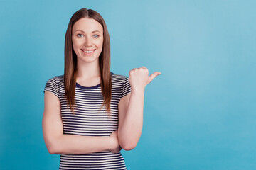 Fototapeta premium Portrait of cheerful lovely girl indicate thumb empty space look camera smile on blue background