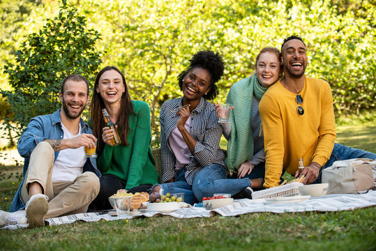 Portrait of smiling young friends having picnic in public park