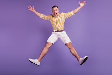 Fototapeta na wymiar Portrait of crazy astonished guy jump star pose dance on purple background