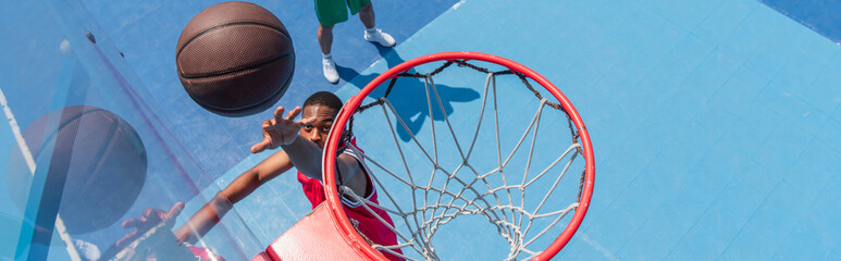 Top view of african american sportsman throwing basketball ball in hoop on playground, banner