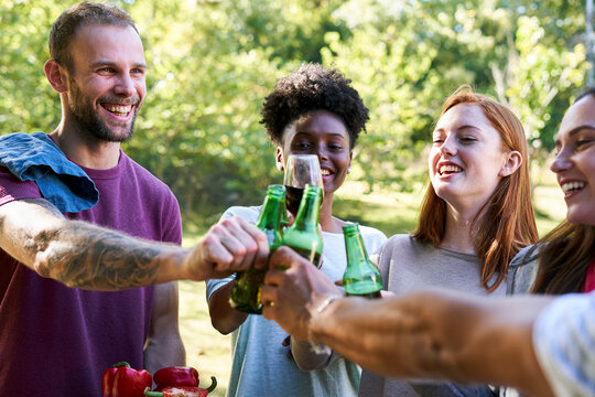 Happy young friends toasting beer bottles in garden