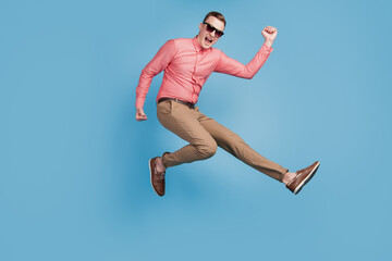 Fototapeta na wymiar Portrait of astonished excited cool guy jump run winner concept on blue background