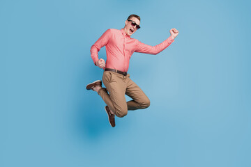 Fototapeta na wymiar Portrait of champion active guy jump celebrate victory on blue background