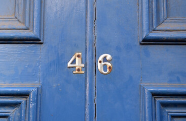 Close up of Brass Number '46' on Old Painted Wooden Door 
