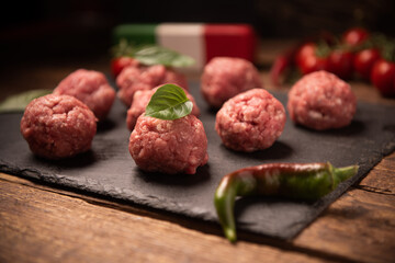 Raw meatballs on  dark basalt plate