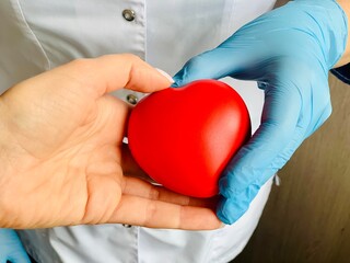 Red heart in hands in blue medical gloves.