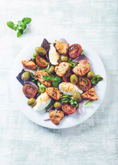 Salad with green olives, cherry tomatoes, chicken and eggs. Wooden background. Top view. Copy space. 	