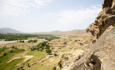 In the distance there are green mountains, a river, a rocky ledge, rocks. Georgia.
