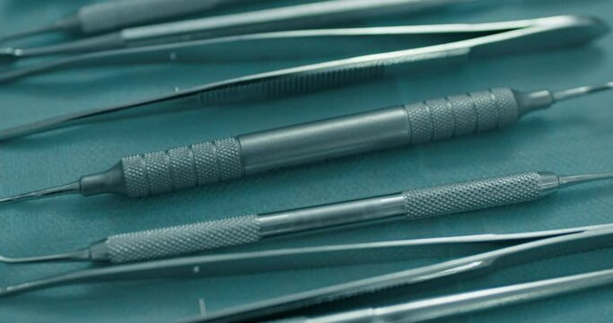 Close-up metal dental tools are laying on the table such as dental mirror, scaler, curettes,  probes, and tweezers.