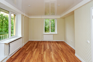 Empty bright room with a wooden floor and light wallpaper. The apartment is after renovation.