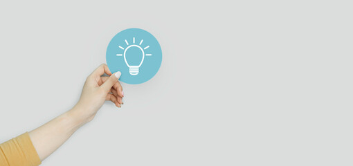 Idea innovation and inspiration concept, Woman hand holding light bulb icon on blue paper cut, concept creativity with bulbs that shine glitter, Inspiration ideas for sustainable business development