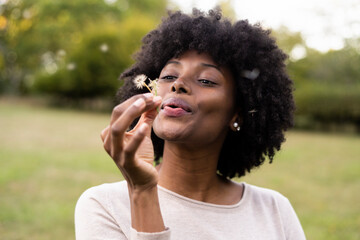 Young woman blowing dandelion flower