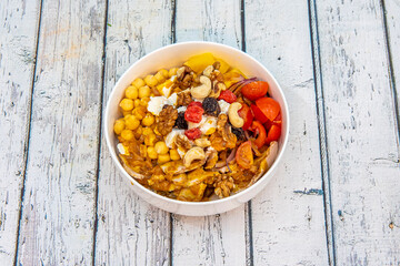 Indian-style food bowl with chickpeas, cashews, cherry tomatoes, California walnuts, dried fruits, ripe mango, goat cheese and red onion