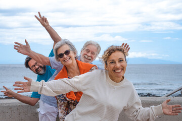 Playful group of family having fun together in outdoor excursion at sea, smiling carefree. Parents,...