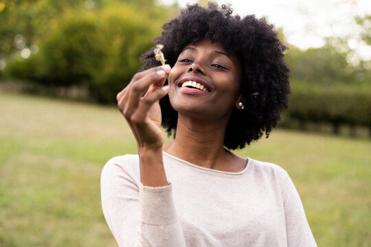 Young woman blowing dandelion flower