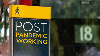 Post Pandemic working sign in a busy commuter city center