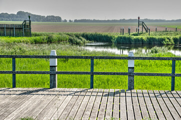 Fototapeta na wymiar Schokland, The Netherlands, August 12, 2021: view from the reconstructed harbour constructions towards the polder that used to be sea untill the early 1940's