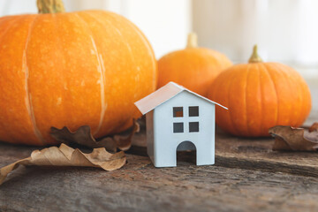 Autumnal Background. Toy house and pumpkin on wooden background. Thanksgiving banner copy space....
