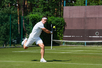 Young sportsman running while playing tennis on court