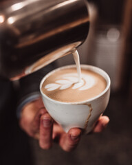Hands of a barista in the process of making cappuccino coffee in a cafe - training and practice