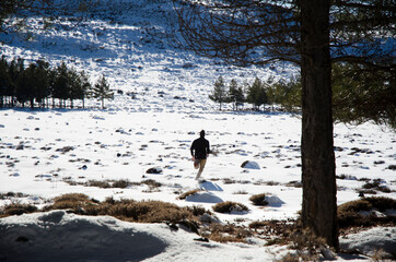 man running between the trees of a forest in a snowy place