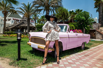Summer fashion. Beautiful sexy elegant woman in polka dot dress near the pink car on Cuba Havana....