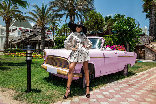Summer fashion. Beautiful sexy elegant woman in polka dot dress near the pink car on Cuba Havana. Spring and summer fashion model concept. Vintage and retro style. Luxury travel.
