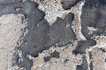 a bad asphalt road that has been repaired many times