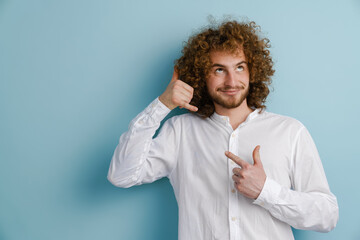Young curly man with ginger hair pointing finger at his gesture