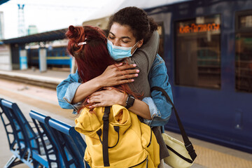 Multiracial two women hugging while saying goodbye at train station