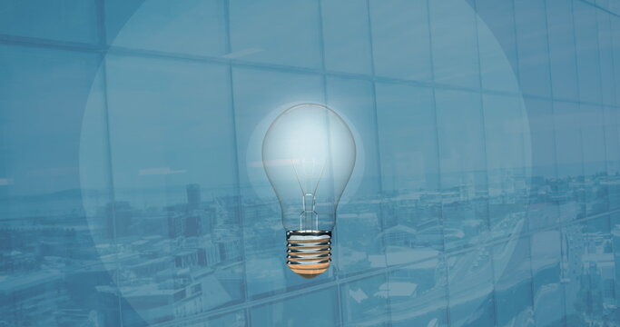 Image of light bulb over office on blue background
