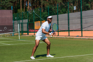 Concentrated african american sportsman playing tennis on court outdoors