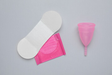 Menstrual cup and disposable pantyliners on grey background, flat lay