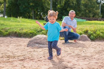 Dad and daughter have fun playing in the sun by the pond on the beach. Sincere emotions of a happy family.