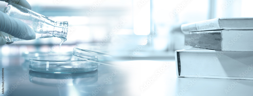 Wall mural scientist holding flask with petri dish and stack of book in research science lab banner background