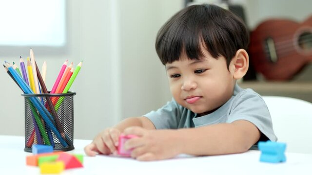 Asian little boy education from home. Developing children's learning before entering kindergarten Practice the skills of playing with wooden toys and drawing and painting.
