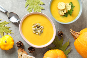 Concept of tasty food with pumpkin soup on gray textured table