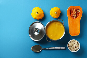 Concept of tasty food with pumpkin soup on blue background