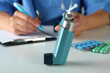 Inhaler against nurse sitting at the table and writing