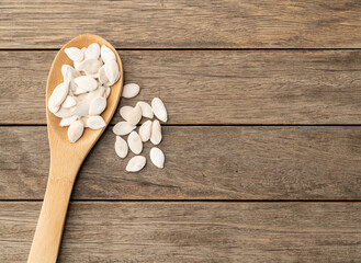 Shelled pumpkin seeds in a spoon over wooden table with copy space
