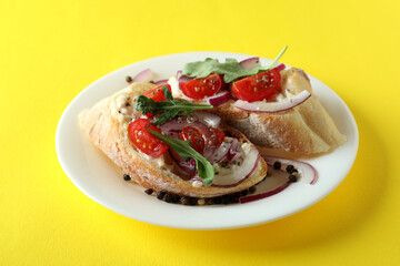 Plate with bruschetta snacks on yellow background