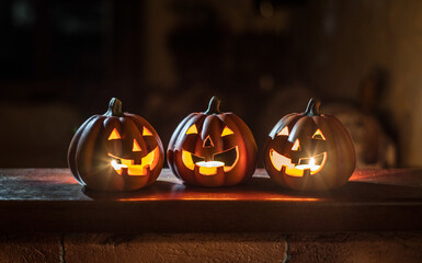 Illuminated Halloween Carved Pumpkins on wooden table. Holiday background.