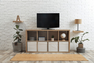 Modern TV set near white brick wall in living room