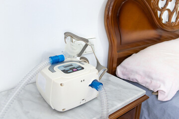 CPAP machine with air hose and head mask on bedside table