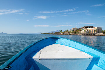 Boat approaching the Malecon in the bay of Loreto with architecture on the background in a summer morning and a blue sky